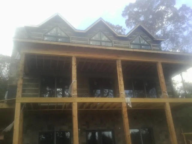 Dormers and porch framing on a large log home under construction — Roof Coating work by our crew in Benton